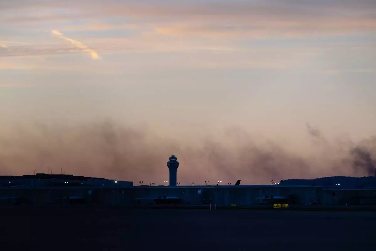 CORRECTS FLIGHT NUMBER The ATC tower is seen while smoke rises from the crash site of UPS Flight 2976 near Louisville Muhammad Ali International Airport on Wednesday, Nov. 5, 2025, in Louisville, Ky. (AP Photo/Jon Cherry)