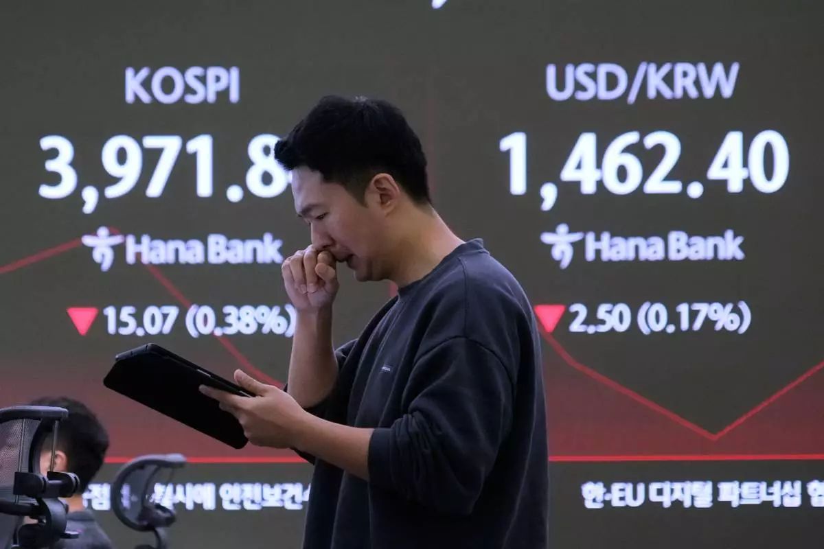 A currency trader works near a screen showing the Korea Composite Stock Price Index (KOSPI), left, and the foreign exchange rate between U.S. dollar and South Korean won at the foreign exchange dealing room of the Hana Bank headquarters in Seoul, South Korea, Friday, Nov. 28, 2025. (AP Photo/Ahn Young-joon)