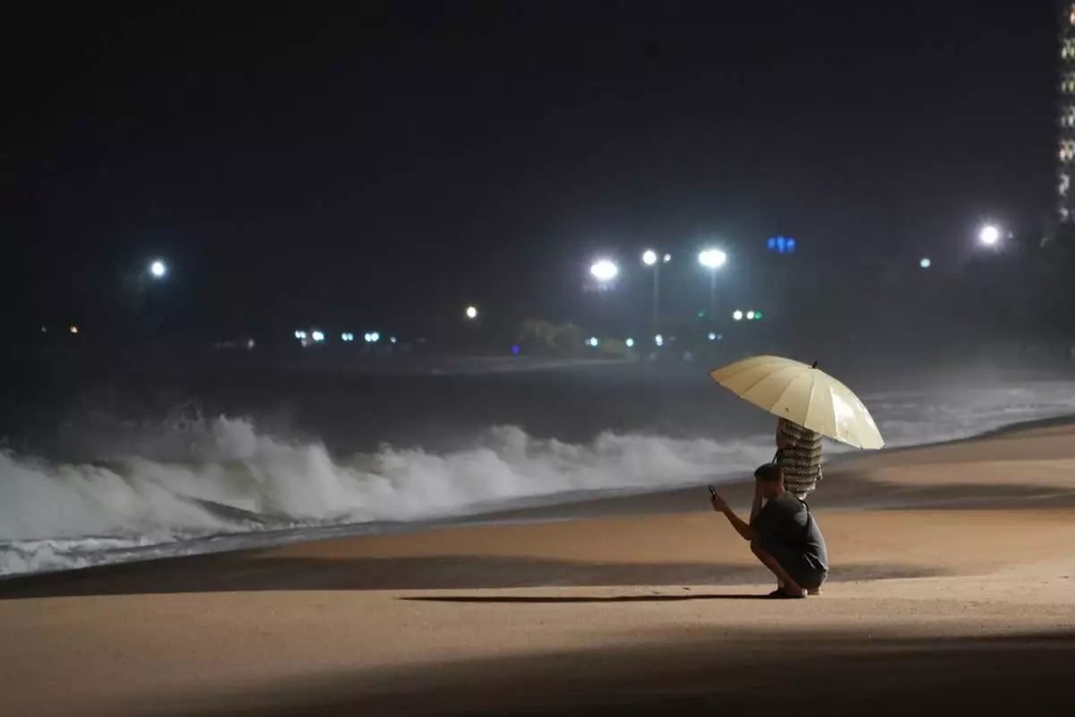 People watch rough waves caused by Typhoon Kalmaegi in Khanh Hoa, Vietnam, Thursday, Nov. 6, 2025. (AP Photo/Hau Dinh)
