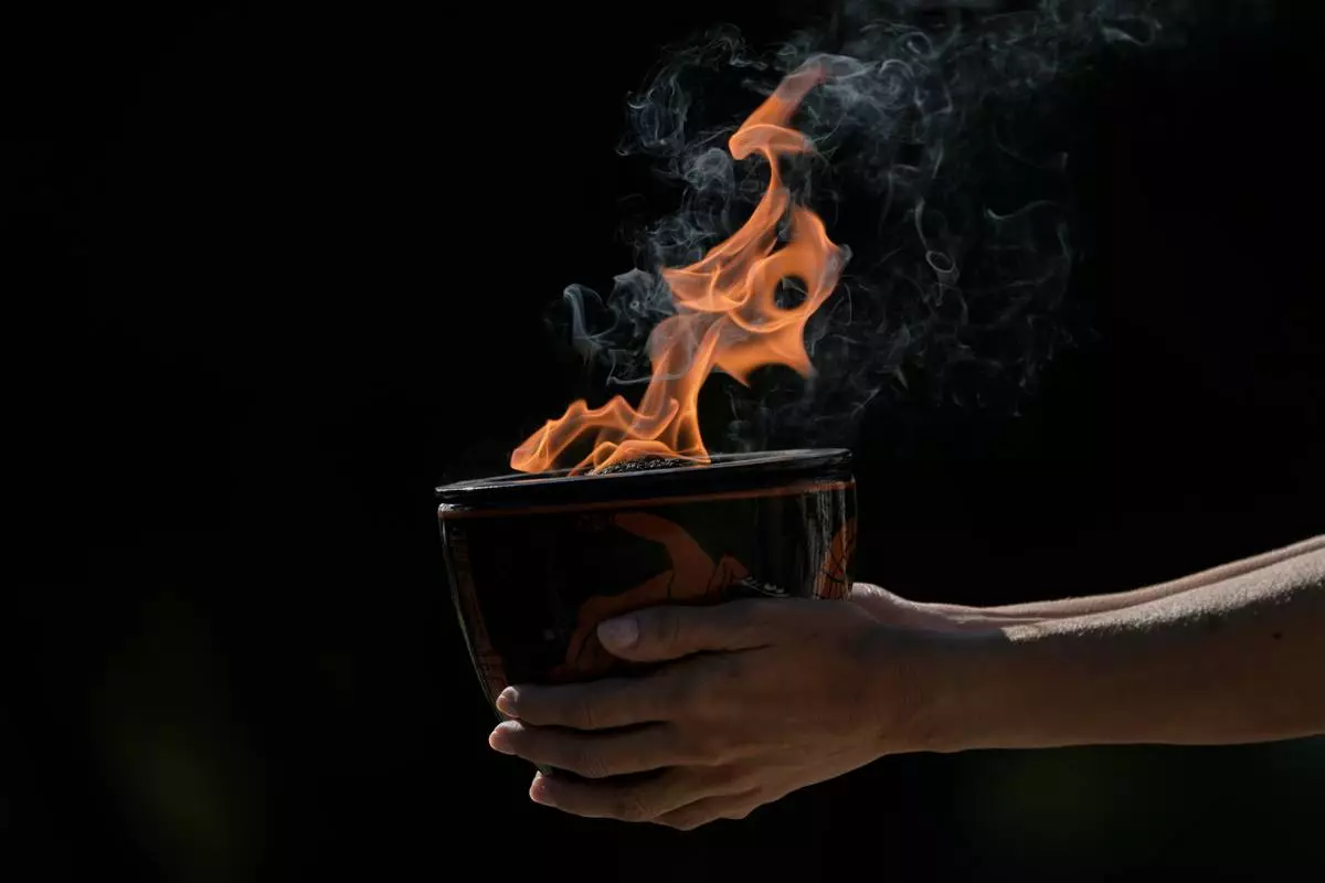 A performer holds a ceramic pot with the flame during a rehearsal ahead of the flame lighting for the Milan Cortina 2026 Winter Olympics, at the Ancient Olympia site, Greece, Monday, Nov. 24, 2025. (AP Photo/Petros Giannakouris)