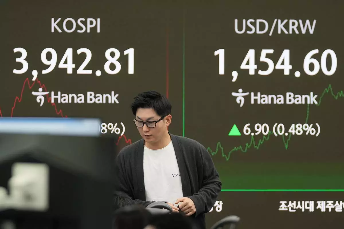 A dealer walks past near the screens showing the Korea Composite Stock Price Index (KOSPI), left, and the foreign exchange rate between U.S. dollar and South Korean won at a dealing room of Hana Bank in Seoul, South Korea, Friday, Nov. 7, 2025. (AP Photo/Lee Jin-man)