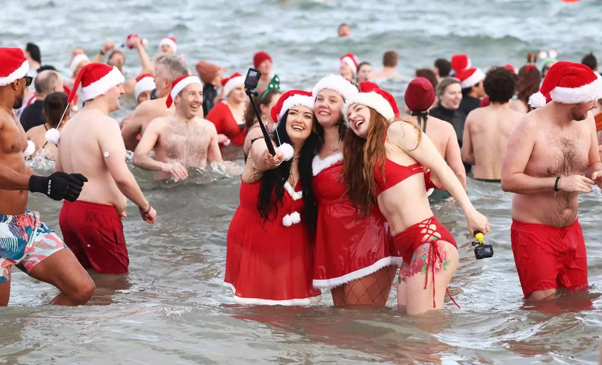 People take to the sea at Helen's Bay, Northern Ireland, for the annual Christmas Eve swim in the cold waters in Belfast Lough to raise money for Dementia NI &amp; Air Ambulance NI, Wednesday, Dec. 24, 2025. (AP Photo/Peter Morrison)