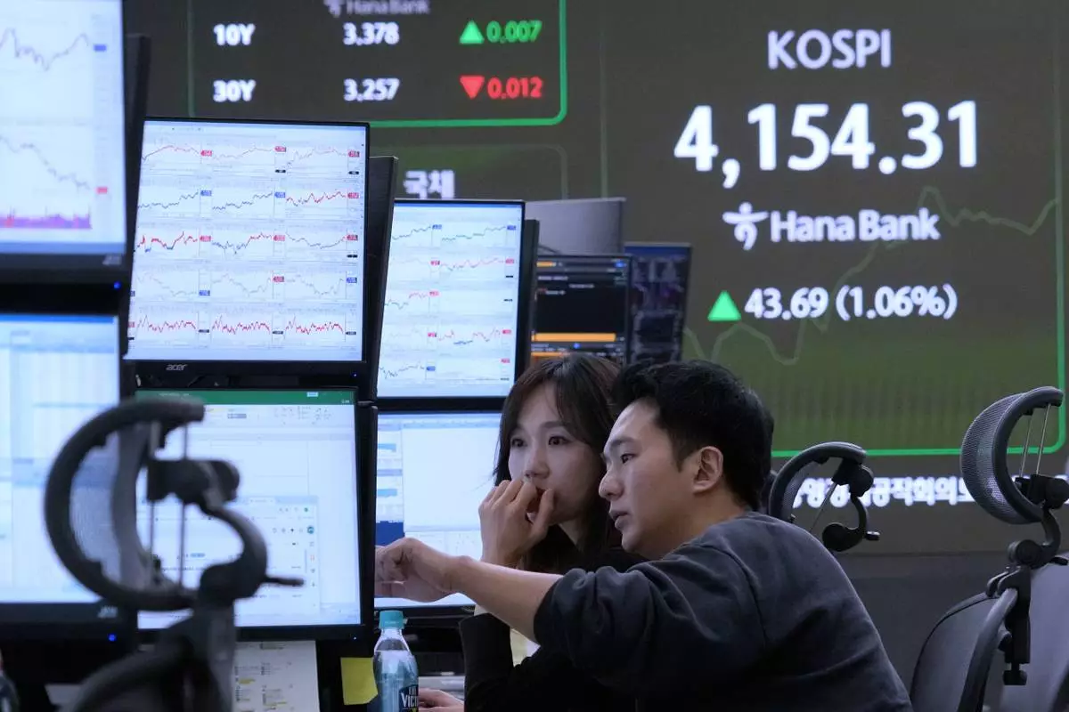 Currency traders watch monitors near a screen showing the Korea Composite Stock Price Index (KOSPI) at the foreign exchange dealing room of the Hana Bank headquarters in Seoul, South Korea, Friday, Dec. 12, 2025. (AP Photo/Ahn Young-joon)