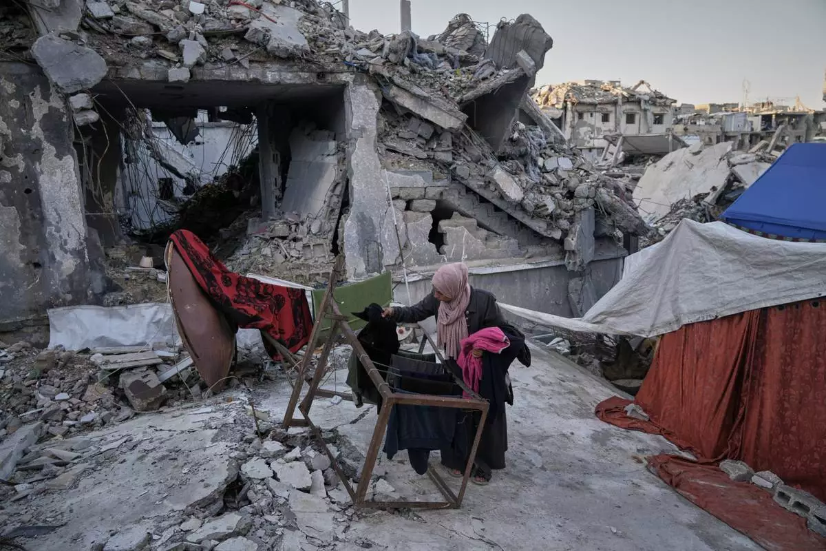 Saadia Abu Duheir, a mother of six, hangs laundry beside a tent set up over the rubble of her family's collapsed home in the Sheikh Radwan neighborhood of Gaza City, Wednesday, Nov. 26, 2025. (AP Photo/Jehad Alshrafi)