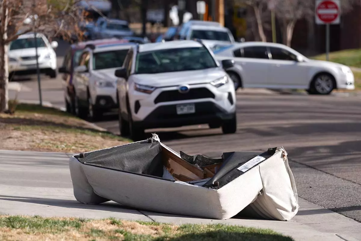 A couch that was blown off the balcony of a high-rise condominium building sits crumpled after falling to the street as hurricane-force winds whipped through the area Thursday, Dec. 18, 2025, in Denver. (AP Photo/David Zalubowski)