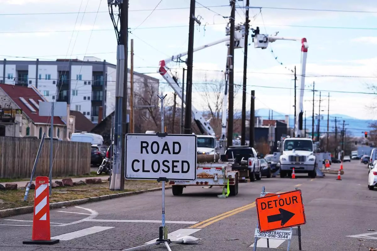 Xcel Energy workers work to repair power lines on a street closed after hurricane-force winds whipped through the metropolitan area and interrupted service to residents, Thursday, Dec. 18, 2025, in Denver. (AP Photo/David Zalubowski)