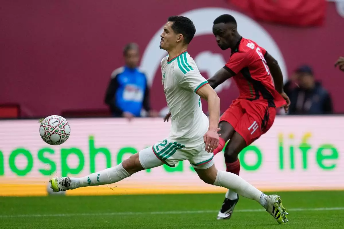 Sudan's Mo Eisa, right, takes a shot at goal next to Algeria's Aïssa Mandi during the Africa Cup of Nations group E soccer match between Algeria and Sudan in Rabat, Morocco, Wednesday, Dec. 24, 2025. (AP Photo/Mosa'ab Elshamy)