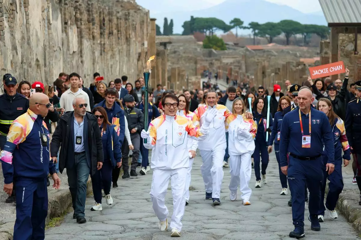 Actor Jackie Chan holds the olympic torch passing through the Archaeological Park in Pompeii, Italy, Monday, Dec. 22, 2025. (Alessandro Garofalo/LaPresse via AP)