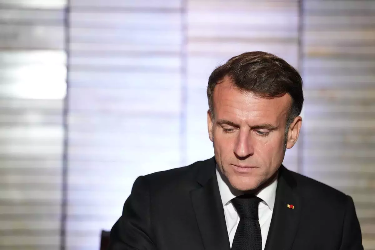 French President Emmanuel Macron signs a register as he attends a commemoration ceremony for French people who fought against apartheid, with South Africa's Deputy President Paul Mashatile and South Africa's Minister of Sports, Arts and Culture Gayton McKenzie at Freedom Park in Pretoria, South Africa, Friday, Nov. 21, 2025. (AP Photo/Thibault Camus)