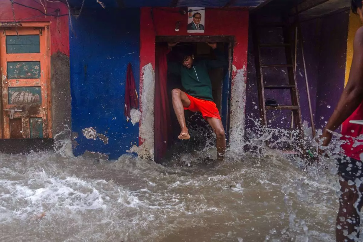 A man jumps as waves lash his house during high tide on the shore of the Arabian Sea in Mumbai, India, on June 25, 2025. (AP Photo/Rafiq Maqbool, File)
