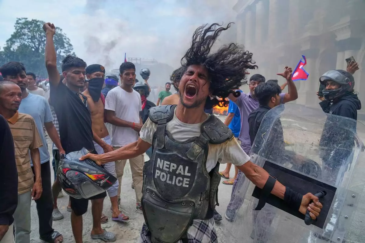 A protester, wearing a flak jacket and carrying a shield snatched from a policeman, shouts outside the Singha Durbar, the seat of Nepal's government, during a protest against corruption and a ban on social media in Kathmandu, on Sept. 9, 2025. (AP Photo/Niranjan Shrestha, File)