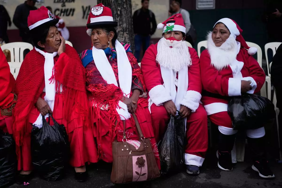 FILE - Women dressed as Santa Claus sit before the annual Christmas parade in La Paz, Bolivia, Dec. 3, 2025. (AP Photo/Juan Karita, File)