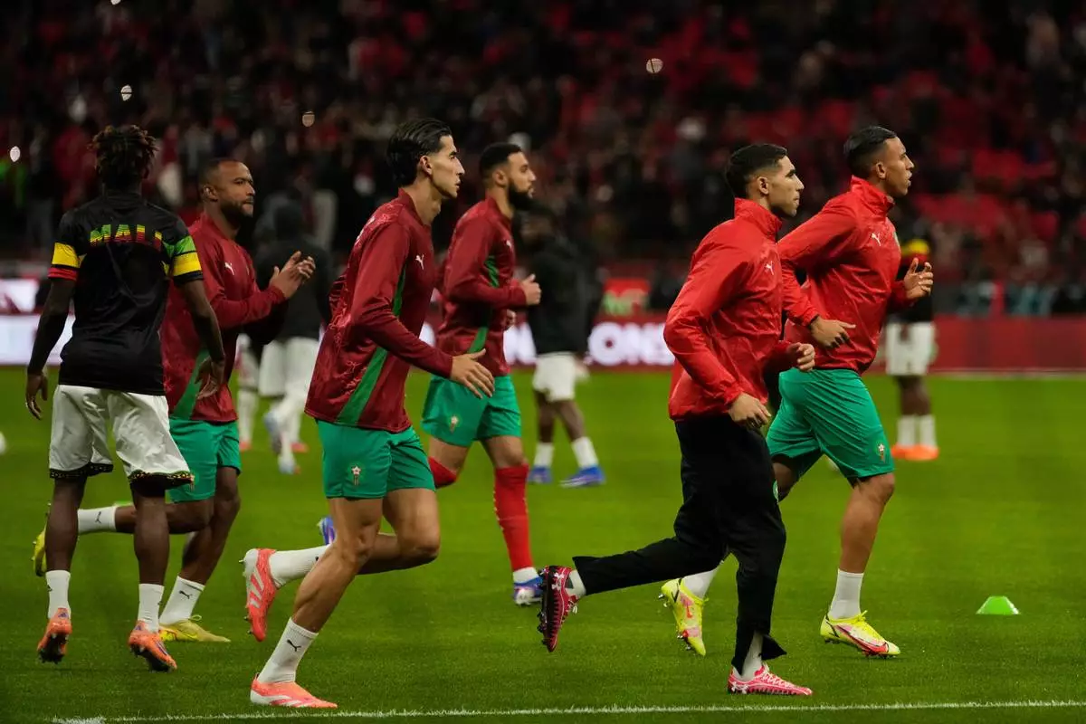 Morocco's Achraf Hakimi second from right, with teammates warm up ahead of the African Cup of Nations Group A soccer match between Morocco and Mali in Rabat, Morocco, Friday, 26, 2025. (AP Photo/Mosa'ab Elshamy)