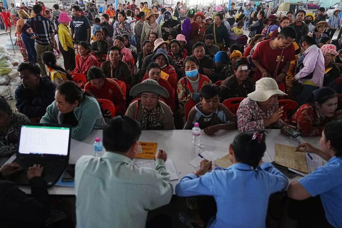 People stay in a line to register at Prey Chamkar Ta Doak market, as they leave the area near the border with Thailand, in Banteay Meanchey province of Cambodia's, Tuesday, Dec. 9, 2025. (AP Photo/Heng Sinith)