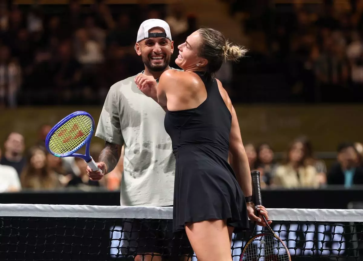 Nick Kyrgios, left, and Aryna Sabalenka interact at the net during their Battle of the Sexes match, in Dubai, United Arab Emirates, Sunday Dec. 28, 2025. (Christopher Pike/Pool Photo via AP)