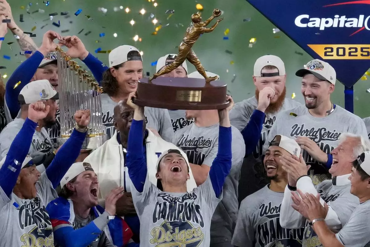 FILE - Los Angeles Dodgers World Series MVP Yoshinobu Yamamoto holds his trophy as teammates celebrate their win in Game 7 of baseball's World Series against the Toronto Blue Jays, Sunday, Nov. 2, 2025, in Toronto. (AP Photo/Ashley Landis, File)