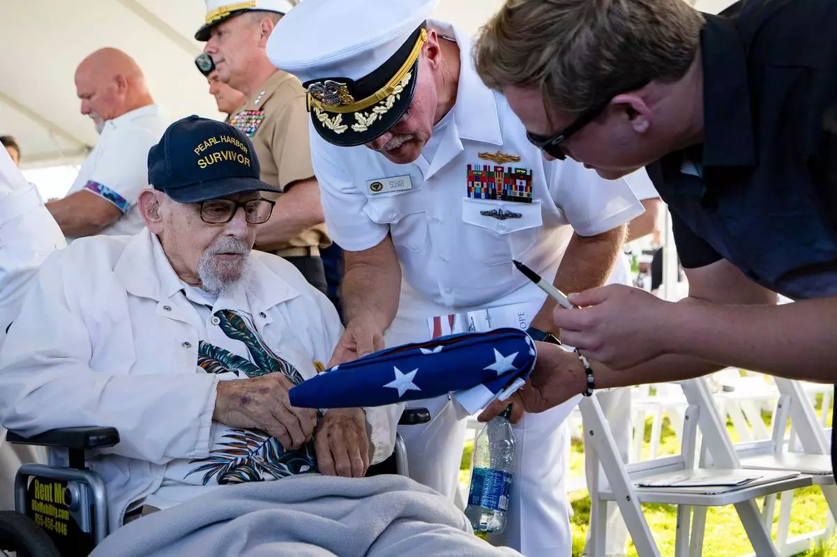 FILE - An attendee asks Pearl Harbor survivor Ira "Ike" Schab, 103, to sign an U.S. flag during the 82nd Pearl Harbor Remembrance Day ceremony on Thursday, Dec. 7, 2023, at Pearl Harbor in Honolulu, Hawaii. (AP Photo/Mengshin Lin, File)