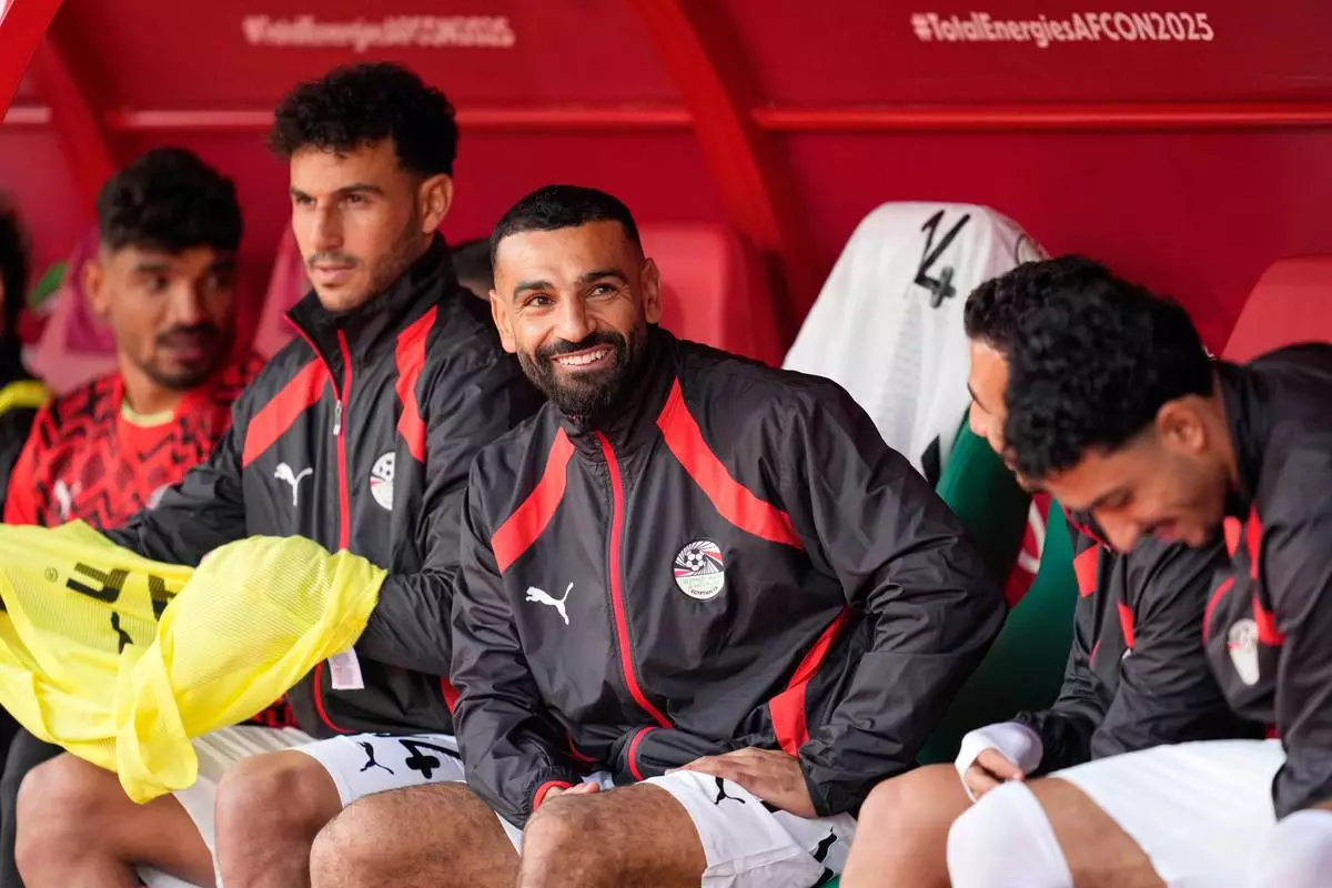 Egypt's Mohamed Salah, center, smiles as he sits on the bench ahead of the Africa Cup of Nations group B soccer match between Angola and Egypt in Agadir, Morocco, Monday, Dec. 29, 2025. (AP Photo/Mosa'ab Elshamy)
