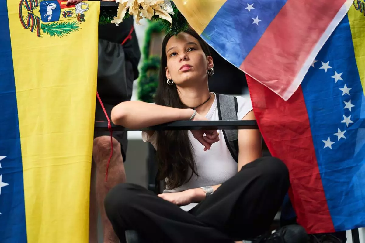 FILE - Framed by Venezuelan national flags, a woman watches a live broadcast of the ceremony in Oslo at which the Nobel Peace Prize was awarded to opposition leader Maria Corina Machado, in Buenos Aires, Argentina, Dec. 10, 2025. (AP Photo/Rodrigo Abd, File)