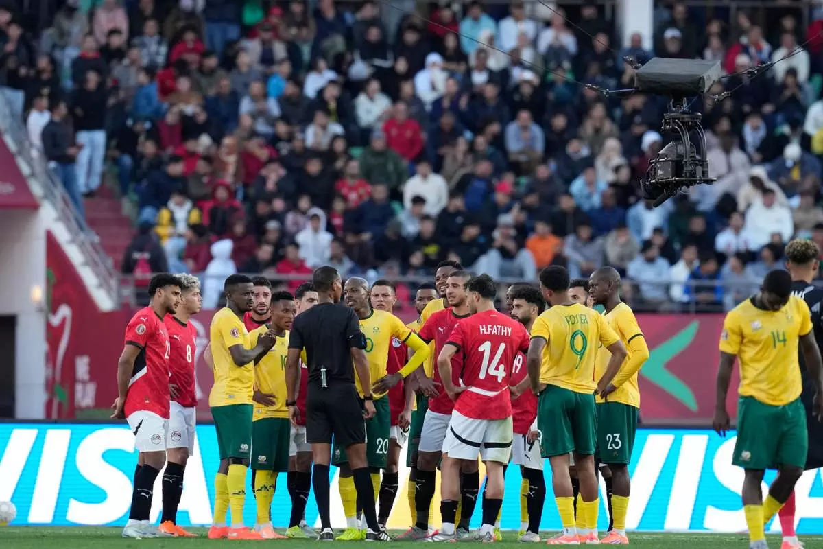 Players gather around the referee Pacifique Ndabihawenimana while a penalty kick check is being conducted during the Africa Cup of Nations group B soccer match between Egypt and South Africa in Agadir, Morocco, Friday, Dec. 26, 2025. (AP Photo/Themba Hadebe)