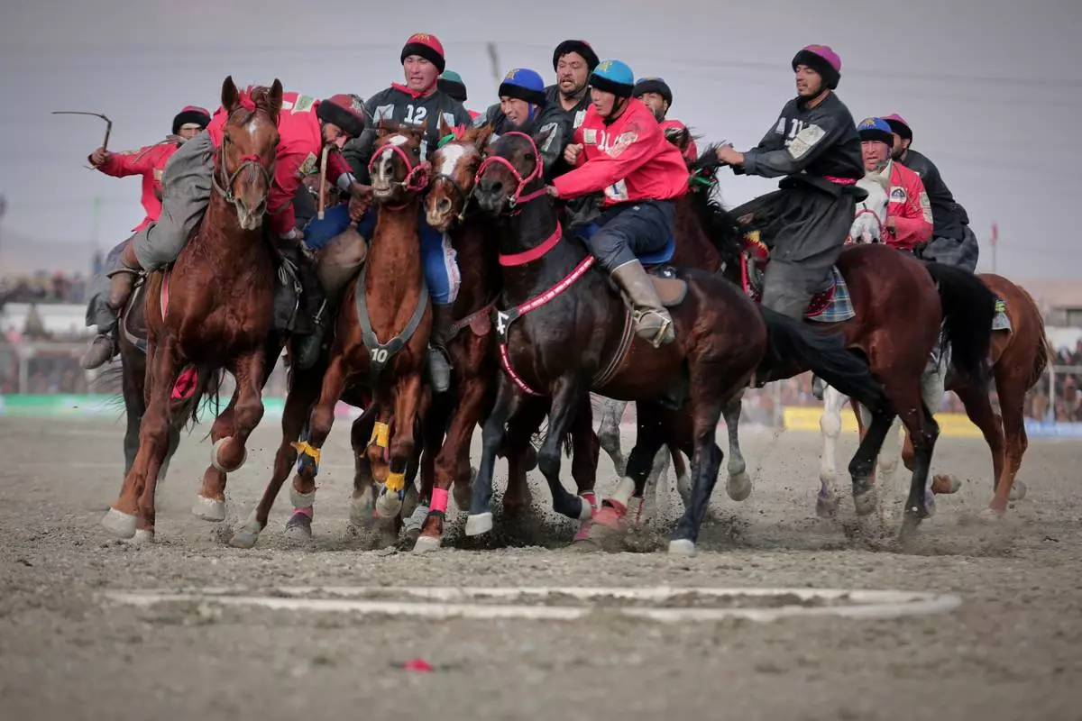 FILE - Riders from the Sar-e-Pul and Badakhshan teams compete in the final of Afghanistan's annual buzkashi tournament, a sport in which riders score points using a fake goat carcass, on the outskirts of Kabul, Afghanistan, Monday, Dec. 22, 2025. (AP Photo, File)