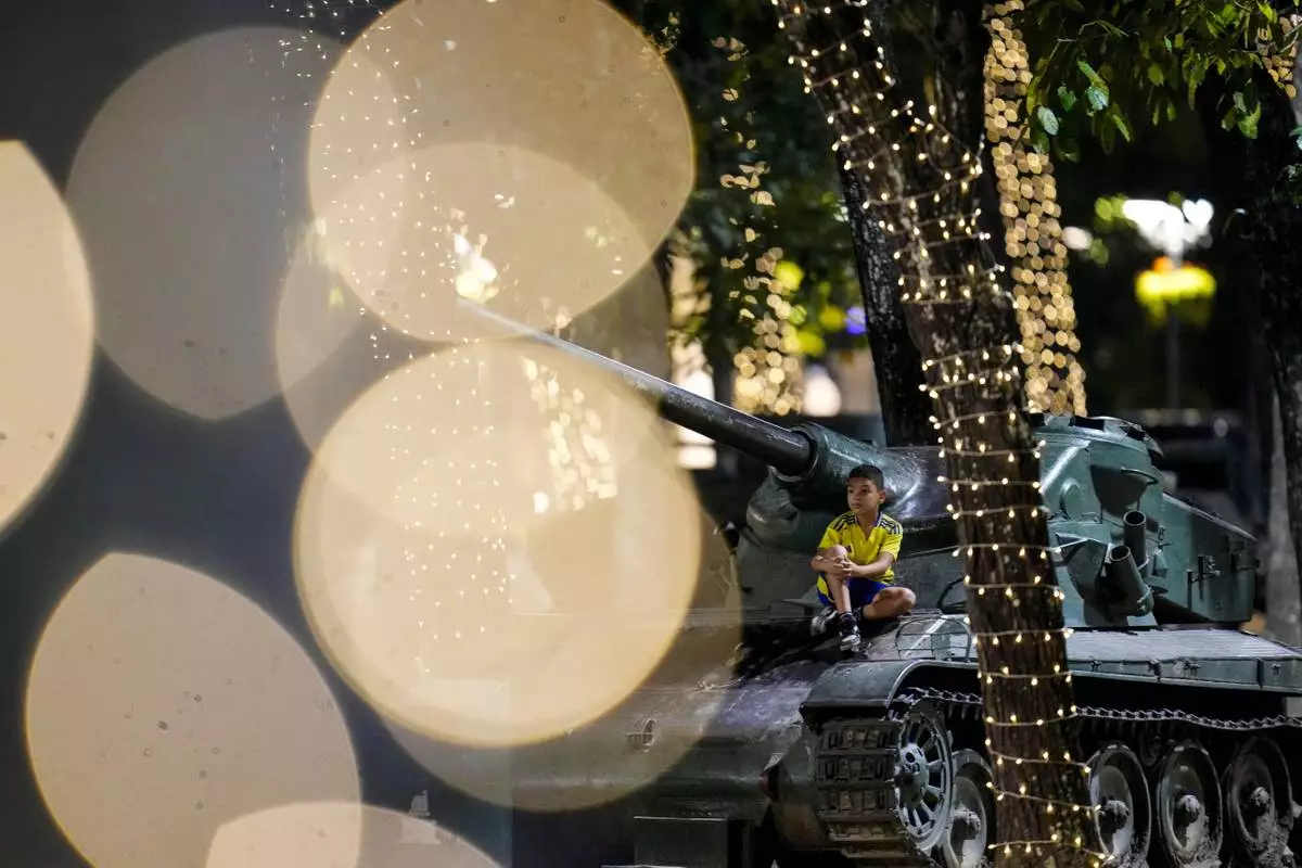 FILE - A child sits on an armored vehicle on display among Christmas lights in Caracas, Venezuela, Tuesday, Dec. 23, 2025. (AP Photo/Matias Delacroix, File)