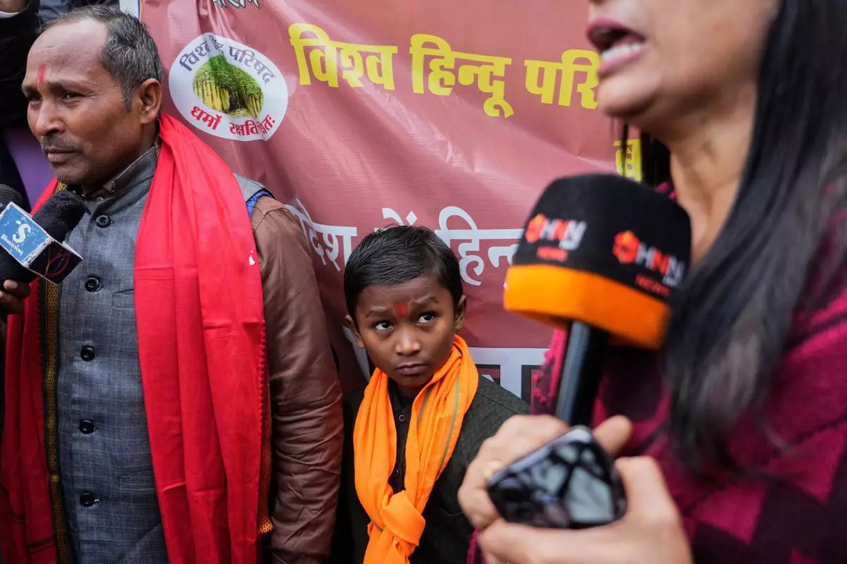 FILE - A boys looks at a journalist covering a protest by Vishwa Hindu Parishad, a prominent right-wing Hindu nationalist organization, accusing Bangladeshi groups of wrongly targeting Indians, in New Delhi, India, Tuesday, Dec. 23, 2025. (AP Photo/Manish Swarup, File)