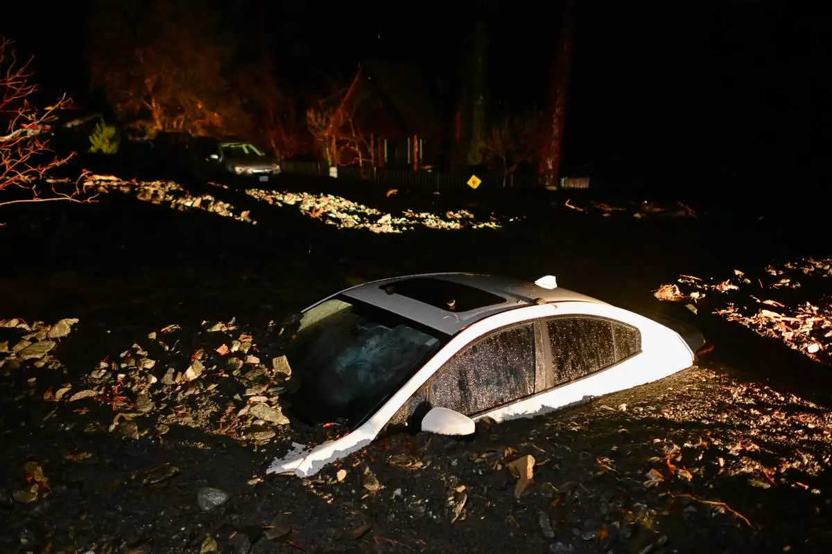 A car sits buried in mud after flooding Wednesday, Dec. 24, 2025, in Wrightwood, Calif. (AP Photo/Wally Skalij)