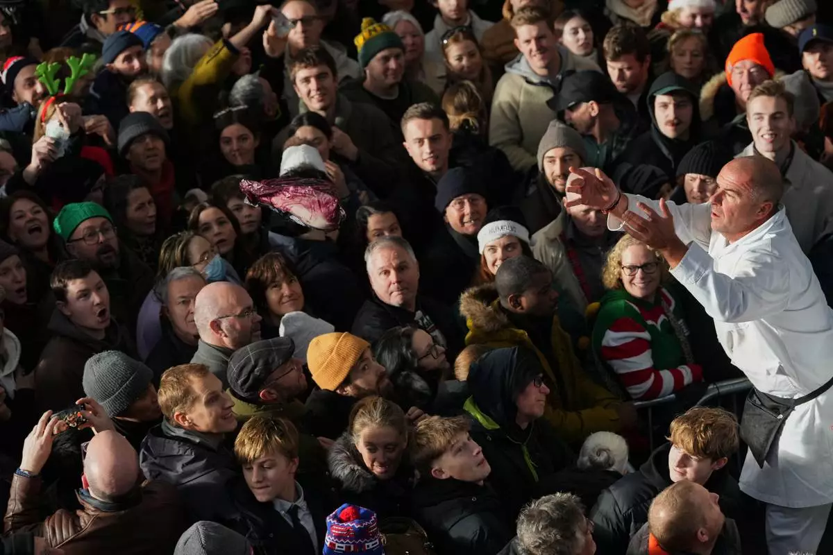 FILE - A piece of meat is thrown to the buyer in the crowd during the annual Christmas Eve meat auction at Smithfield Market in London, Wednesday, Dec. 24, 2025. (AP Photo/Kirsty Wigglesworth, File)