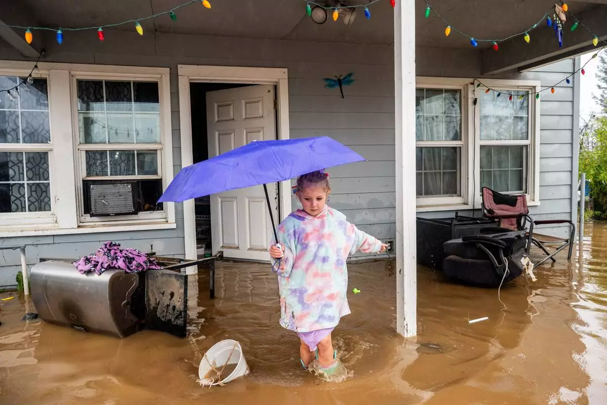 FILE - Aria Wogoman, 5, leaves her flooded home following heavy rain, Monday, Dec. 22, 2025, in Redding, Calif. (AP Photo/Noah Berger, File)