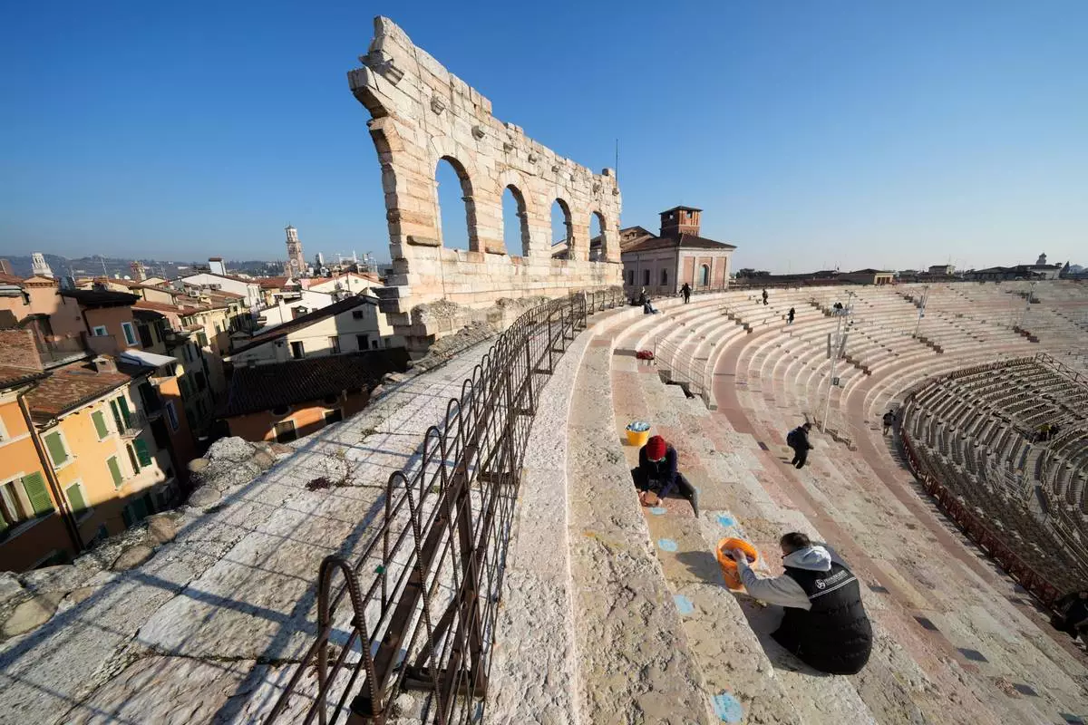A worker removes seat number stickers used to mark places during concerts at the Arena of Verona, Italy, Wednesday, Dec. 10, 2025. (AP Photo/Luca Bruno)
