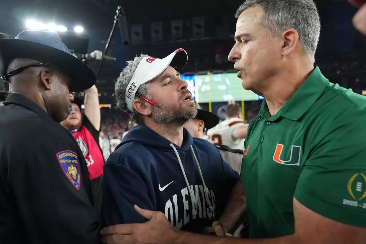CORRECTS TO MISSISSIPPI HEAD COACH PETE GOLDING NOT MISSISSIPPI HEAD COACH MARIO CRISTOBAL - Mississippi head coach Pete Golding, center, greets Miami head coach Mario Cristobal, right, after the Fiesta Bowl NCAA college football playoff semifinal game, Thursday, Jan. 8, 2026, in Glendale, Ariz. (AP Photo/Rick Scuteri)