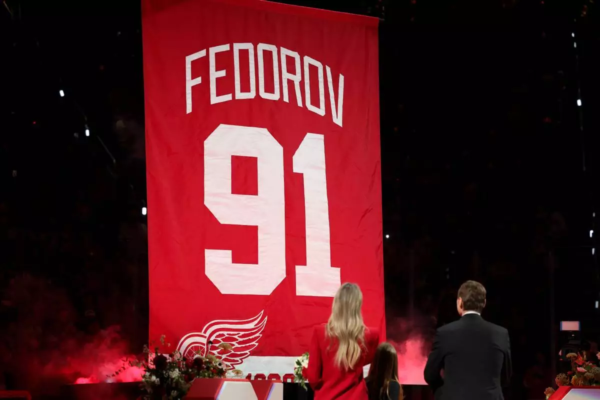 CORRECTS TO SERGEI FEDOROV NOT SERGEI FEDEROV - Former Detroit Red Wings player Sergei Fedorov, right, stands with his wife Karina, left, and children Alexandra and Viktor during his jersey retirement ceremony before an NHL hockey game against the Carolina Hurricanes, Monday, Jan. 12, 2026, in Detroit. (AP Photo/Ryan Sun)