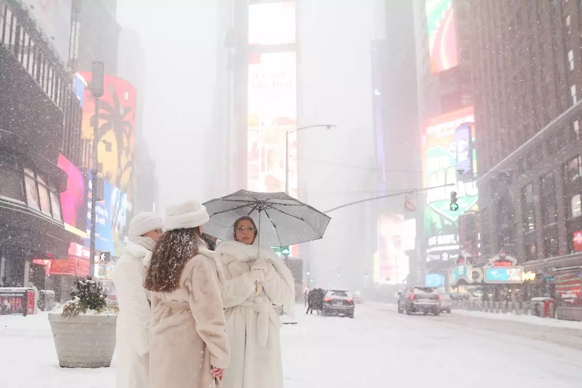 FILE - People wait to cross the street in Times Square during a winter storm, Sunday, Jan. 25, 2026, in New York. (AP Photo/Heather Khalifa, File)
