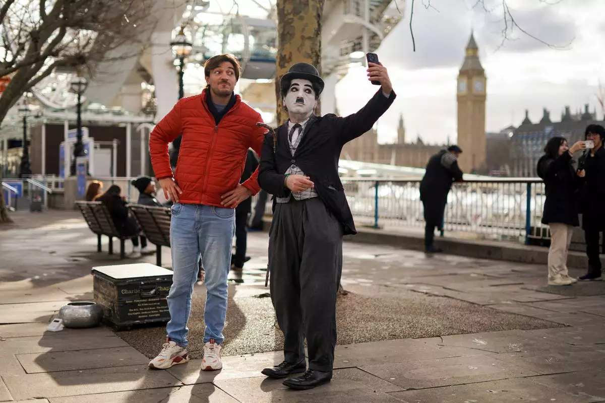FILE - A man takes a selfie with a street artist in a costume, in London, Wednesday, Jan. 28, 2026.(AP Photo/Alberto Pezzali, File)