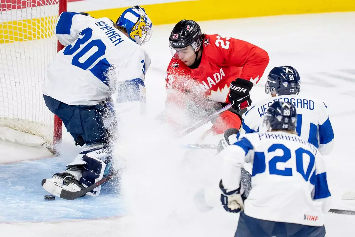 Canada's Sam O'Reilly, center, scores on Finland goaltender Petteri Rimpinen (30) while teammates Kasper Pikkarainen (20) and Max Westergard, second from right, defend during the first period of an IIHF World Junior Hockey Championship bronze medal game in St. Paul, Minn., Monday, Jan. 5, 2026. (Christopher Katsarov/The Canadian Press via AP)