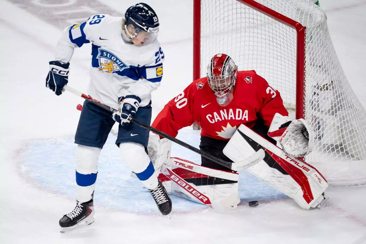 Finland scores on Canada goaltender Carter George (30) while Finland's Jasper Kuhta (29) stands in front of the net, during the first period of an IIHF World Junior Hockey Championship bronze medal game in St. Paul, Minn., Monday, Jan. 5, 2026. (Christopher Katsarov/The Canadian Press via AP)