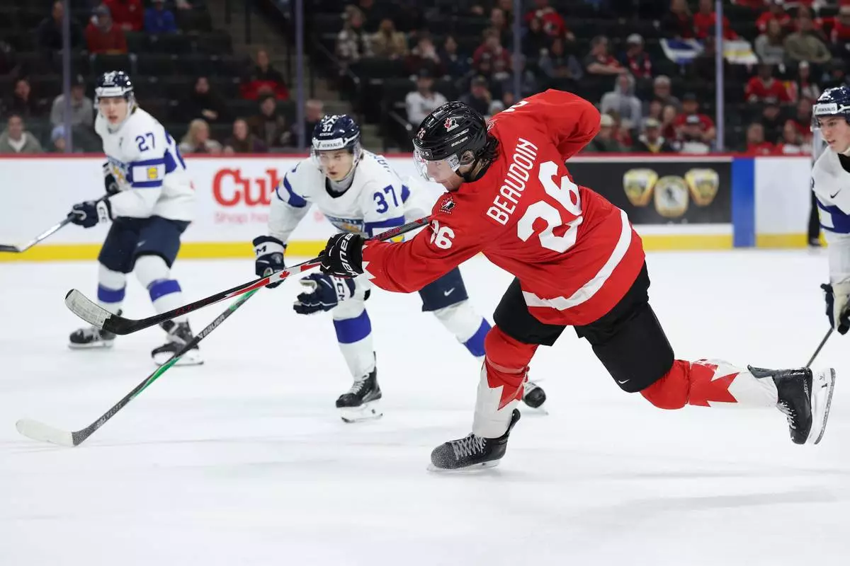 Canada forward Cole Beaudoin (26) shoots against Finland forward Matias Vanhanen (37) during the second period of an IIHF World Junior Hockey Championship bronze medal game, Monday, Jan. 5, 2026, in St. Paul, Minn. (AP Photo/Matt Krohn)