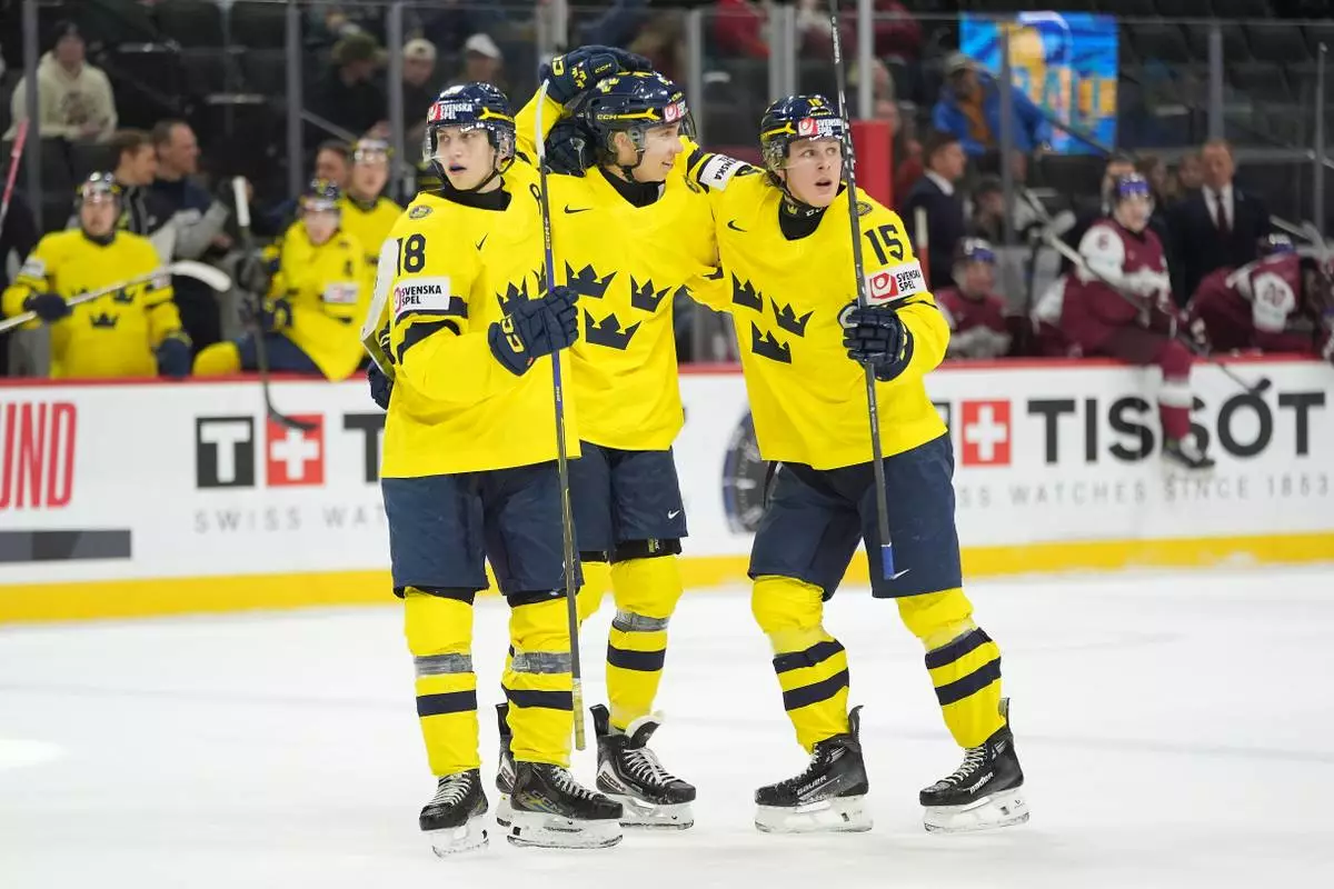 Sweden defenseman Sascha Boumedienne, center, celebrates with forwards Victor Eklund, left, and Sweden Ivar Stenberg, right, after scoring a goal during the second period of an IIHF World Junior Hockey championship quarterfinal game against Latvia, Friday, Jan. 2, 2026, in St. Paul, Minn. (AP Photo/Abbie Parr)