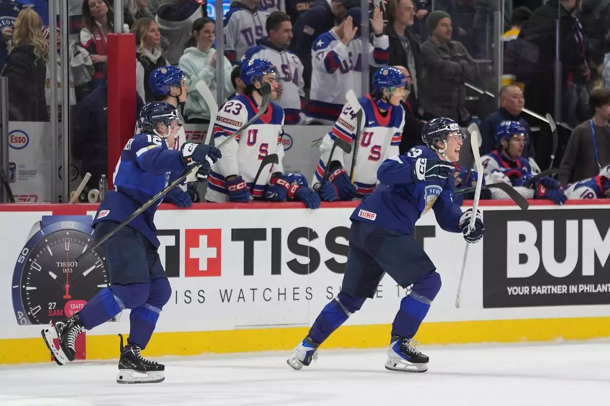 Finland forwards Joona Saarelainen (12), left, and forward Leo Tuuva (23) celebrate after the overtime win against the United States of an IIHF World Junior Hockey Championship quarterfinals game, Friday, Jan. 2, 2026, in St. Paul, Minn. (AP Photo/Abbie Parr)
