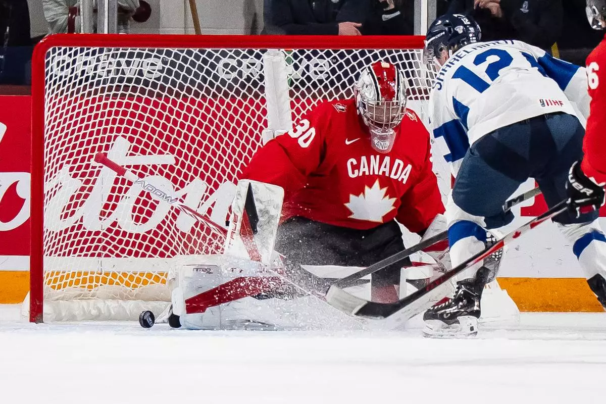 Canada goaltender Carter George (30) makes a save on Finland's Joona Saarelainen (12) during first period IIHF World Junior Championship hockey action in Minneapolis on Wednesday, Dec. 31, 2025. (Christopher Katsarov/The Canadian Press via AP)
