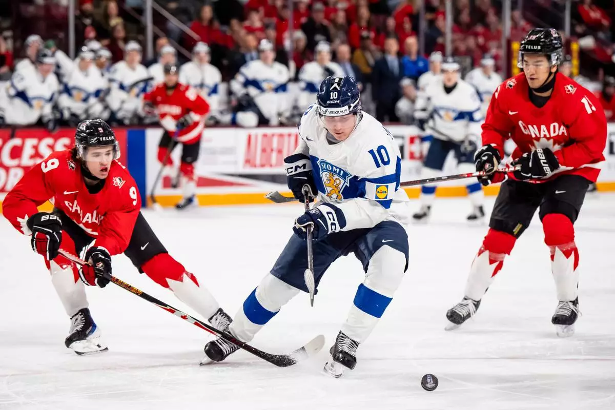 Finland's Roope Vesterinen (10) skates with the puck while Canada's Gavin McKenna (9) and Zayne Parekh (19) defend during second period IIHF World Junior Championship hockey action in Minneapolis on Wednesday, Dec. 31, 2025. (Christopher Katsarov/The Canadian Press via AP)