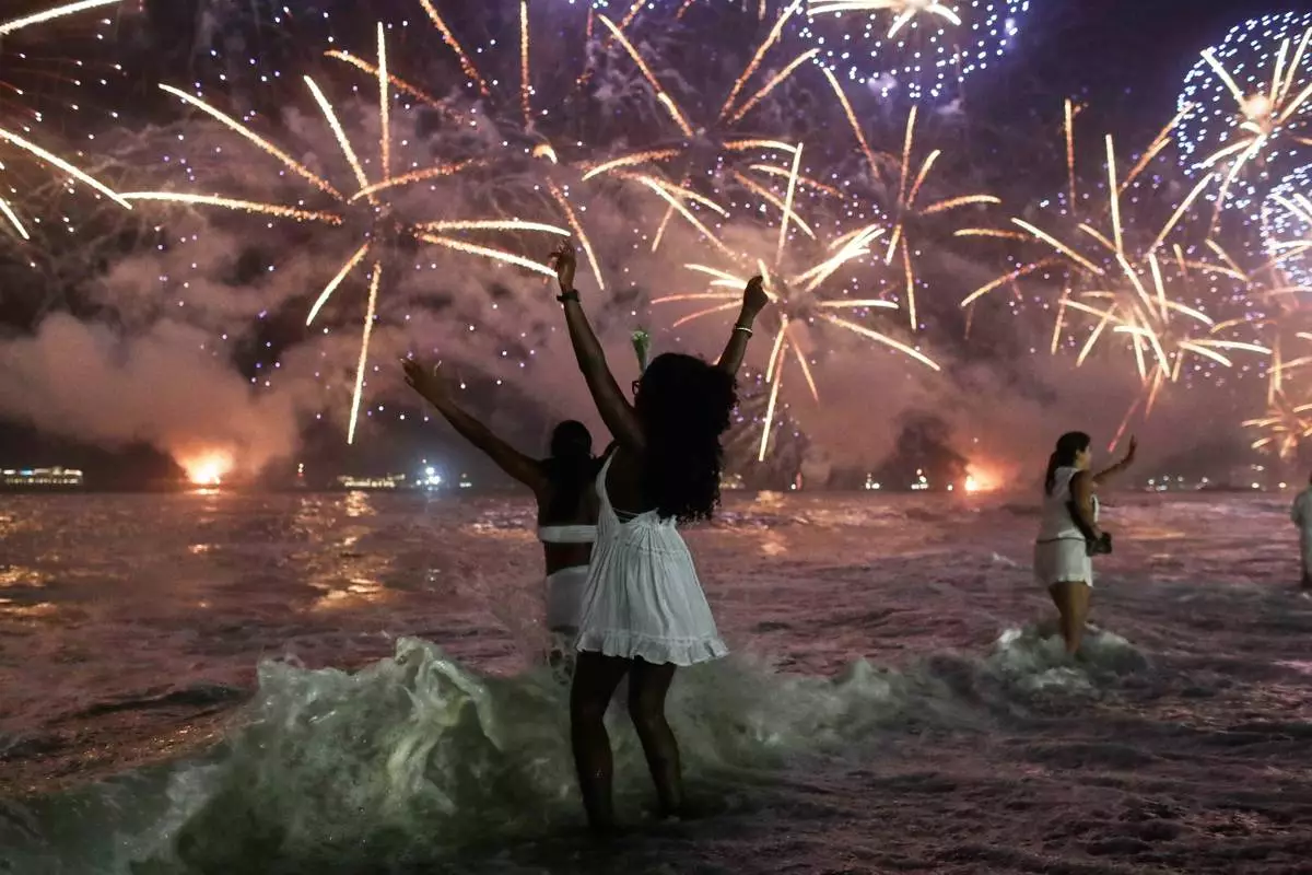 FILE - People celebrate as fireworks light up the sky over Copacabana Beach during New Year's celebrations in Rio de Janeiro, Jan. 1, 2026. (AP Photo/Bruna Prado, File)