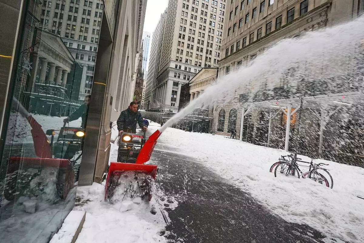 A worker uses a snow blower on Wall Street, in New York, Monday, Jan. 26, 2026. (AP Photo/Richard Drew)