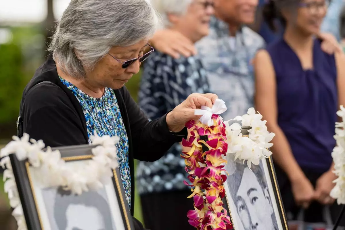 Faith Shiramizu places a lei on a framed photo of her uncle, Howard Urabe, a former University of Hawaii ROTC cadet, after a posthumous commissioning ceremony at Ke'ehi Lagoon Memorial Park, Monday, Jan. 26, 2026, in Honolulu. (AP Photo/Mengshin Lin)