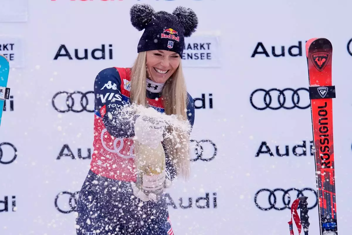 United States' Lindsey Vonn sprays sparkling wine as she celebrates on podium after winning an alpine ski, women's World Cup downhill, in Zauchensee, Austria, Saturday, Jan. 10, 2026. (AP Photo/Giovanni Auletta)