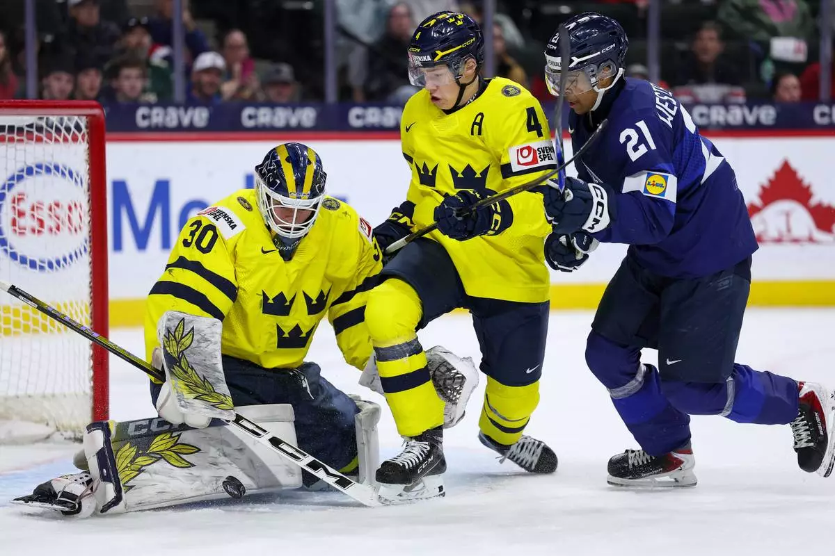 Sweden goalie Love Harenstam, left, defends the net as defenseman Leo Sahlin Wallenius, middle, and Finland forward Max Westergard compete for the puck during the first period of an IIHF World Junior Hockey Championship semifinals game, Sunday, Jan. 4, 2026, in St. Paul, Minn. (AP Photo/Matt Krohn)