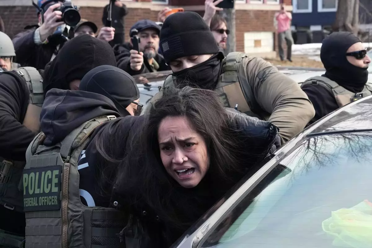 CORRECTS FROM A PROTESTER TO A PERSON - A person is detained by federal agents near the scene where Renee Good was fatally shot by an ICE officer last week, Tuesday, Jan. 13, 2026, in Minneapolis. (AP Photo/Adam Gray)