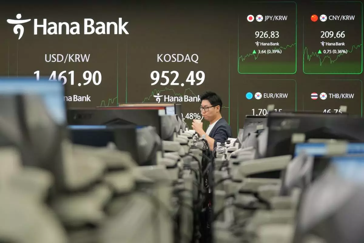 A dealer walks near the screens showing the foreign exchange rate between U.S. dollar and South Korean won and the Korean Securities Dealers Automated Quotations (KOSDAQ) at a dealing room of Hana Bank in Seoul, South Korea, Monday, Jan. 12, 2026. (AP Photo/Lee Jin-man)