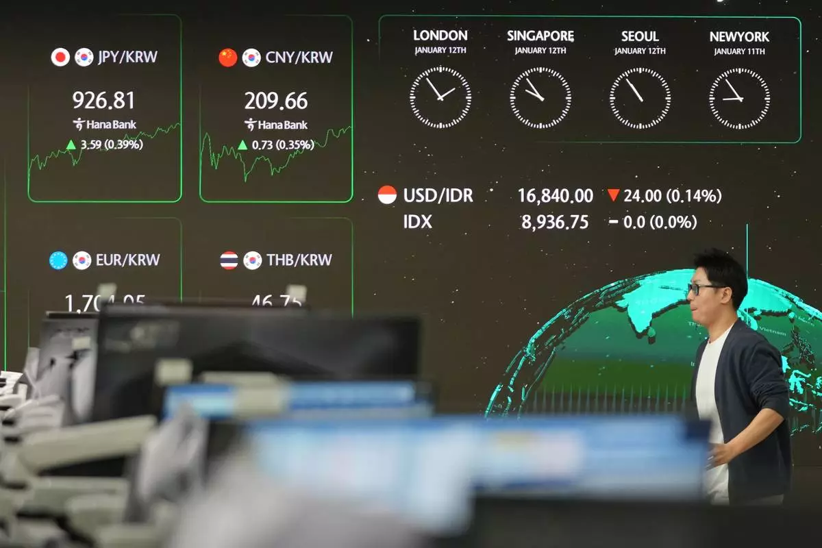 A dealer walks near the screens showing the foreign exchange rates at a dealing room of Hana Bank in Seoul, South Korea, Monday, Jan. 12, 2026. (AP Photo/Lee Jin-man)